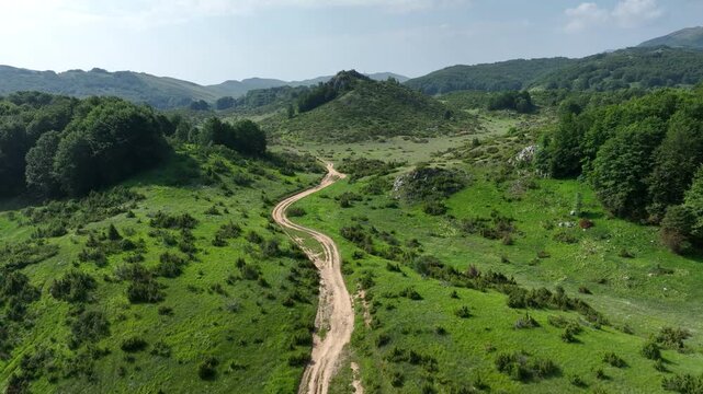 Curved Dirt Road Leading Into Forested Hills in North Macedonia
