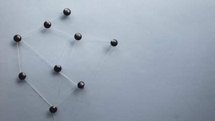 metal tacks attached with thread to a sheet representing a communication network and a dark background
