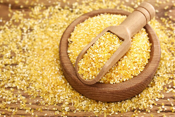 Spoon of coarse semolina on rustic wooden background, gluten free yellow corn grain for healthy...