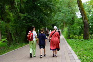 Fototapeta premium Family stroll through a lush park during a sunny afternoon in summer, enjoying nature and each other’s company