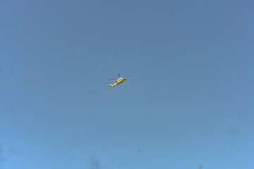 A helicopter is flying in the blue sky.