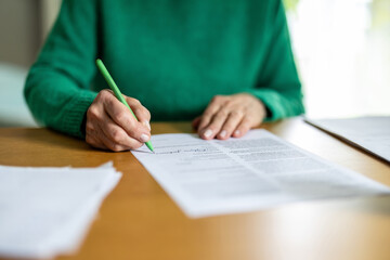 Unrecognizable senior woman signing a document, close-up
