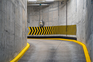 View of turning lane with yellow and black markings in indoor parking garage.