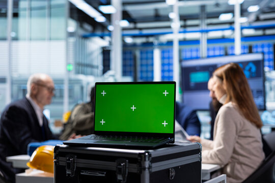 Investors evaluating factory production efficiency using green screen laptop before investing. Shareholders meeting with industrial plant managers to understand business model, using mockup notebook - Powered by Adobe