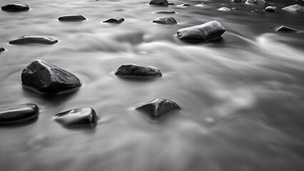 Smooth river stones captured in a minimalist black and white composition, with water flowing gently around them.