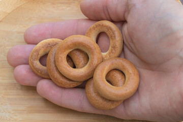 Small Round Bagel-Style Crackers Held in Hand on Wooden Background