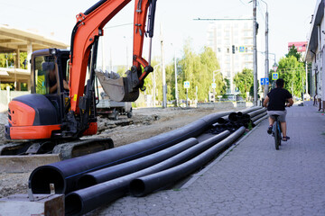 Construction site features machinery and cyclist on sidewalk in urban area during sunny day