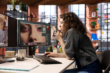Female editor designer retouches photos on dual monitors desktop, computer setup in a creative...