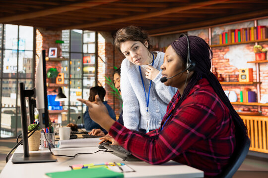 Call center manager supervising agent helping customers regain access to accounts and devices. Customer center supervisor overseeing intern assisting clients needing help resetting password - Powered by Adobe