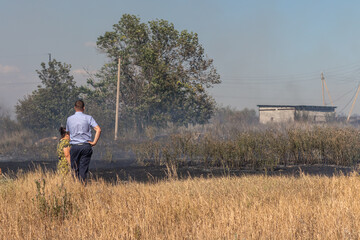 A scorched field after a fire and people looking at it