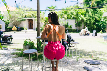 Carefree female freelancer enjoys moment outdoors with coconut drink, eyes closed and face lifted toward sun, embracing freedom of remote tech lifestyle and digital independence.