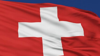 The flag of Switzerland is red with a white cross in the center waving in the wind against a blue sky