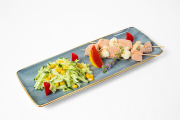 Red fish kebab with cauliflower and fresh salad on a plate on a white background