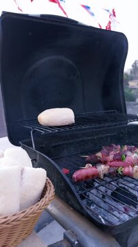 Chilean Independence Day vertical video: Camera pans from basket of marraquetas to grilling anticuchos with festive decorations in background
