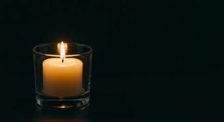 Lit Candle in Glass, Flame Illuminated on a Black Background, Studio Shot, Close Up