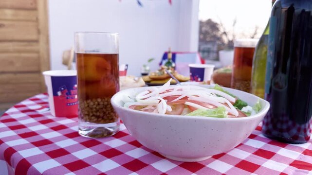 Chilean Independence Day video: Woman&rsquo;s hand placing glass of mote con huesillo on decorated table with Chilean food and terrace background