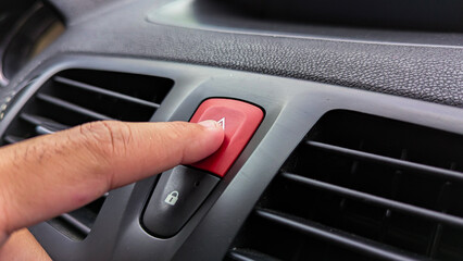 Obraz premium A person's finger presses the red emergency stop button on a car