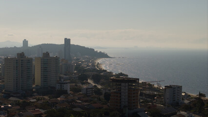 Obraz premium Coastal cityscape of Penha at dusk with high-rise buildings and shimmering ocean in Santa Catarina, Brazil.