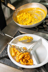 Chef serving saffron risotto with fried seafood in a restaurant kitchen