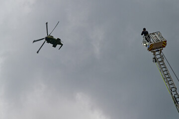 A firefighter from the Flensburg fire brigade films a Danish rescue helicopter on the rescue ladder
