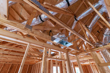 New residential construction showcases wooden beams ductwork being installed in new home setting.