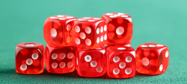 Many red dices on green background, closeup