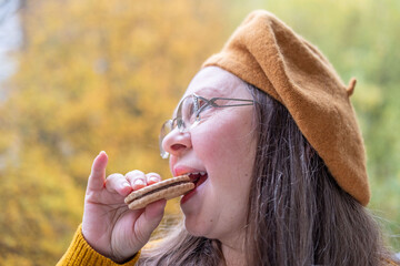 Mature Hungry woman biting sandwich cookies with funny craving expression, comic face expression...