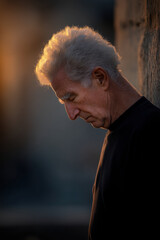 elderly man in silent pain with teary eyes portrayed against clean solid background
