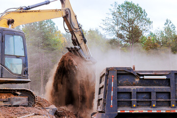 Heavy machinery is seen transferring soil into dump truck amidst clearing activities at works site