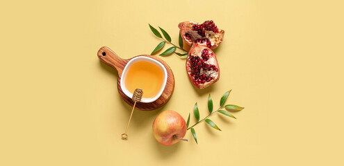 Wooden board with bowl of honey, pomegranate and apple for Rosh Hashanah celebration (Jewish New Year) on yellow background