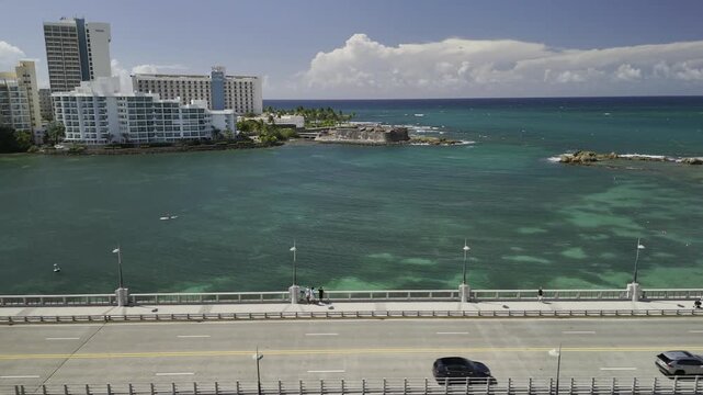 Drone flies north over causeway crossing Laguna del Condado on sunny morning in San Juan, Puerto Rico
