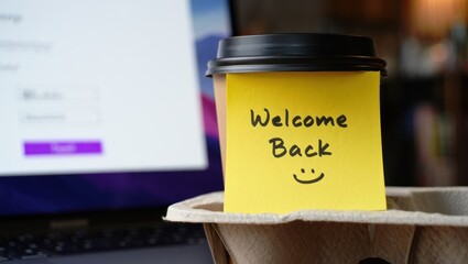 Welcome back greeting on coffee cup in front of laptop
