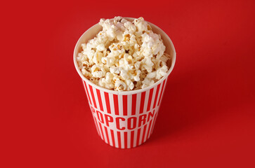 Bucket with tasty popcorn on red background