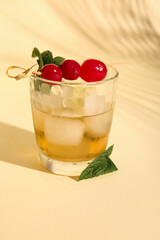 Glass of tasty cocktail with maraschino cherries on yellow background