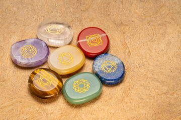 seven chakra stones with symbol engraving on a textured, handmade, bark paper, reiki healing concept