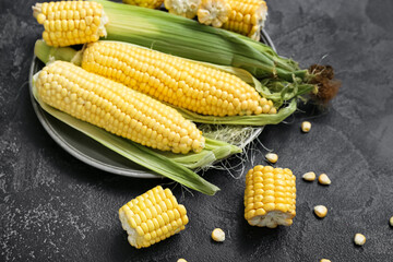 Plate with fresh corn cobs on black table, closeup