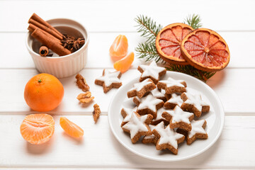 Composition with delicious stars shaped Christmas cookies, orange dried pieces, mandarins, spices and fir tree branch on light wooden background