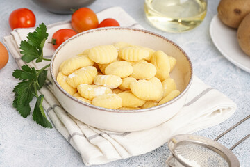 Bowl with tasty gnocchi, tomatoes and parsley on light background, closeup
