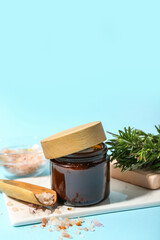 Jar of cosmetic product, sea salt and rosemary on color background