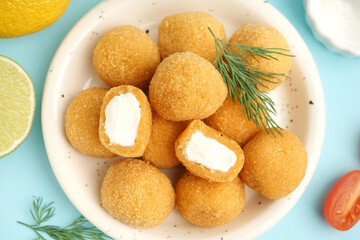 Plate with delicious fried mozzarella balls on blue background, closeup