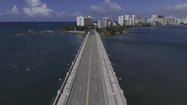 Drone flies east along causeway bridge crossing the mouth of Laguna del Condado on sunny morning in San Juan, Puerto Rico
