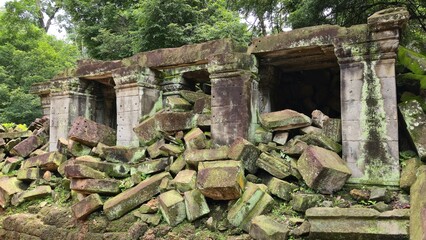 Ta Prohm, Cambodia - 3 July 2025. Fallen stone blocks and pillars of an ancient temple surrounded by dense forest.