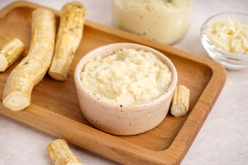 Horseradish sauce in bowls and jar with ground horseradish on white background