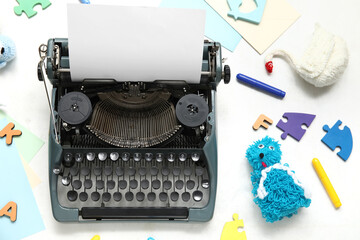 Composition with vintage typewriter, knitted toys and paper on white background