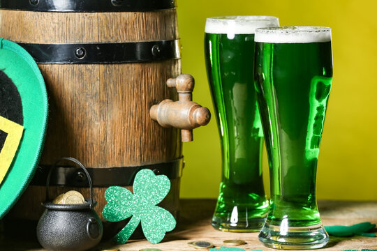 Glasses of green beer with barrel, pot full of coins, Leprechaun's hat and clover leaf on green background. Closeup. St. Patrick's Day celebration.