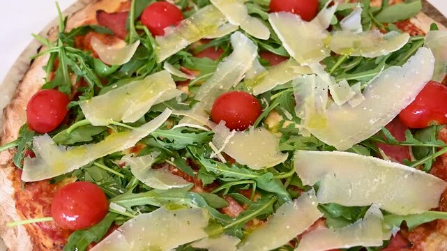Pizza served on a plate in a restaurant. Capricciosa pizza with cheese, salami, mushrooms, arugula and tomatoes.