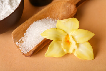 Wooden scoop with vanilla sugar and flower on color background, closeup