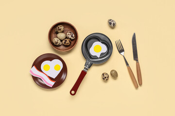 Heart-shaped frying pan with paper fried eggs and quail eggs on beige background