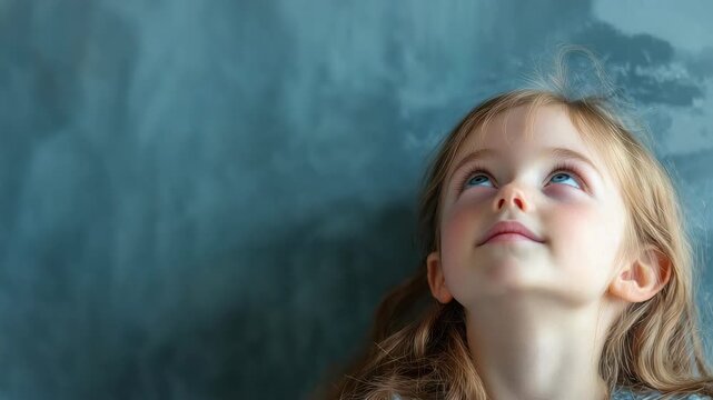 Young girl with long hair looking up against grey backdrop