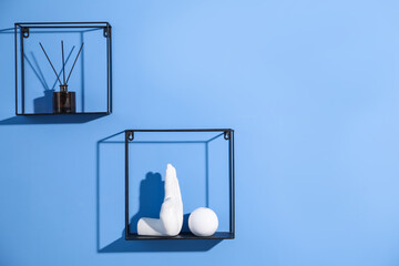 Metal shelves with stylish decor on blue background. Space for text